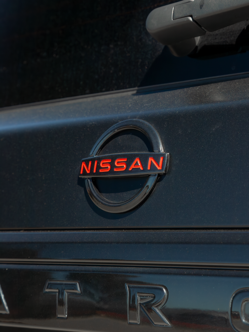 Blacked out Nissan badge with red accents on rear of matte black Y62 Patrol