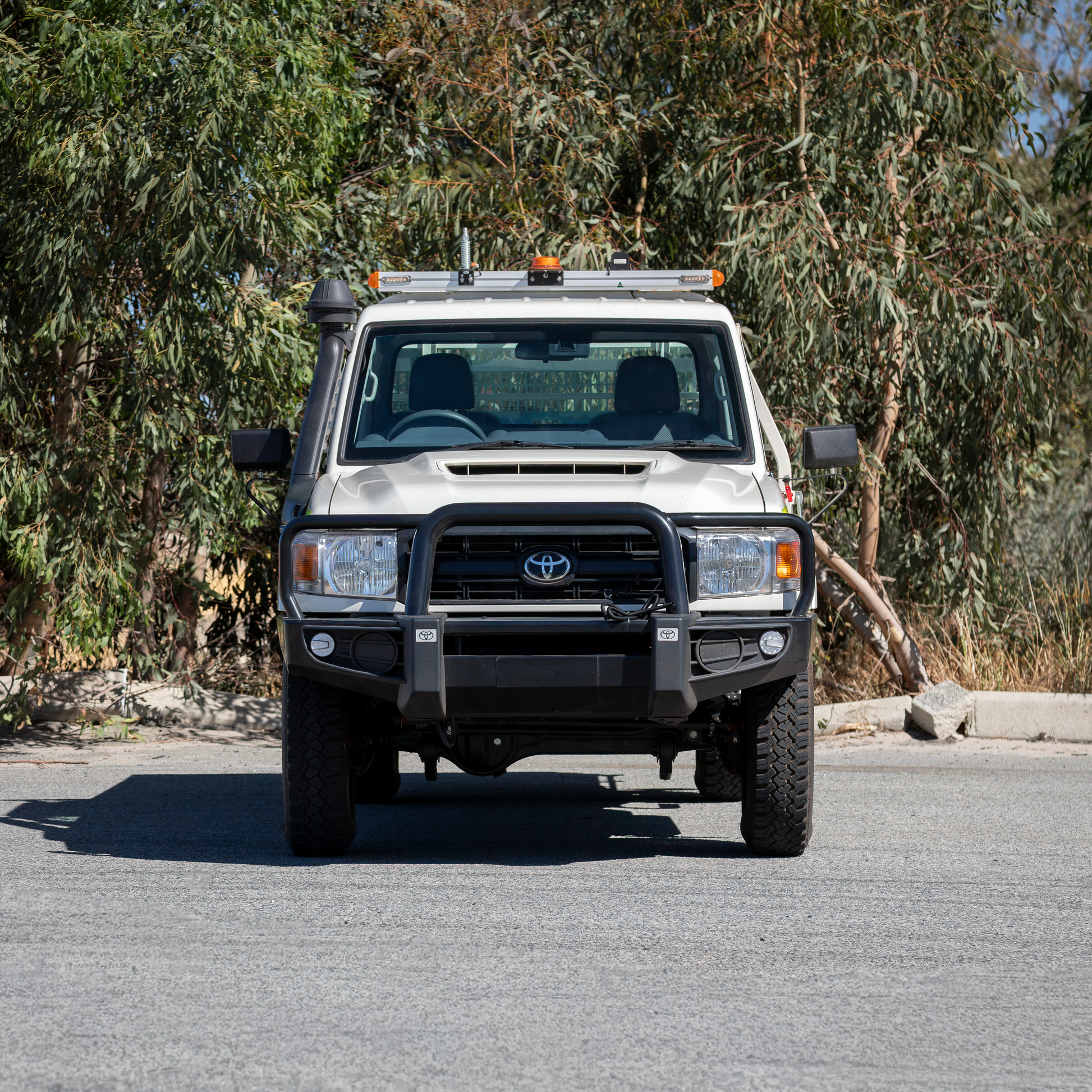 Front view of a mine spec Toyota 79 Series parked in front of green leafy backdrop