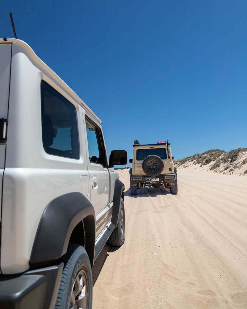 Two JB74 Suzuki Jimny's, Koishi and AMV Automotive's Syvecs build, on white beach