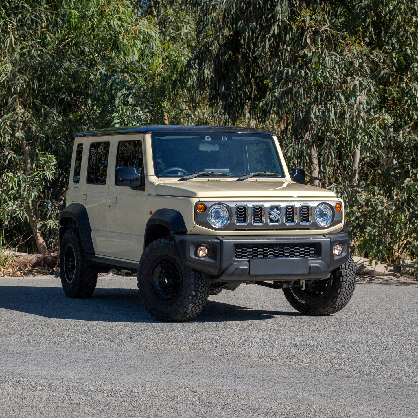Chiffon Ivory/Sandy Suzuki Jimny XL JC74  parked in front of green leafy backdrop