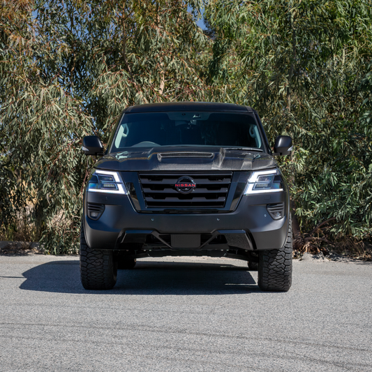 Front view of black Nissan Y62 with blacked out badges and a carbon fibre bonnet.